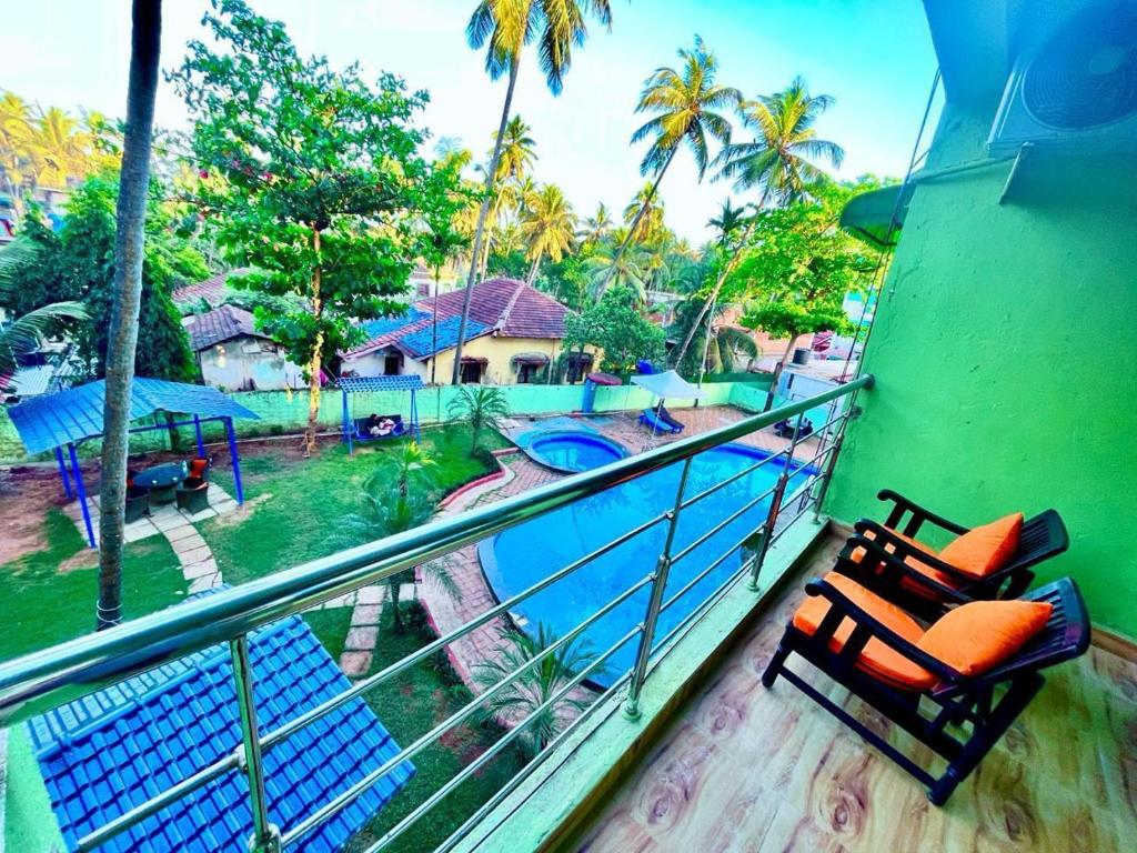 a balcony with two chairs and a swimming pool at The Goa Beach Resort - Best Selling Property in Goa in Calangute