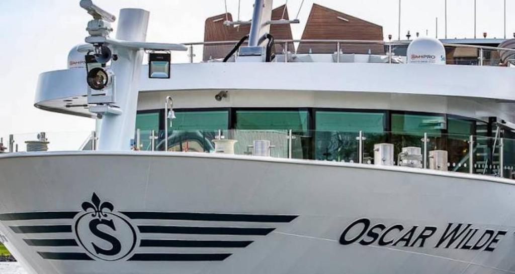 Hotelships Holland, "Oscar Wilde" Messe Hotelboat, a white boat with an ocean wide logo on it at Hotelships Holland, "Oscar Wilde" Messe Hotelboat in Düsseldorf