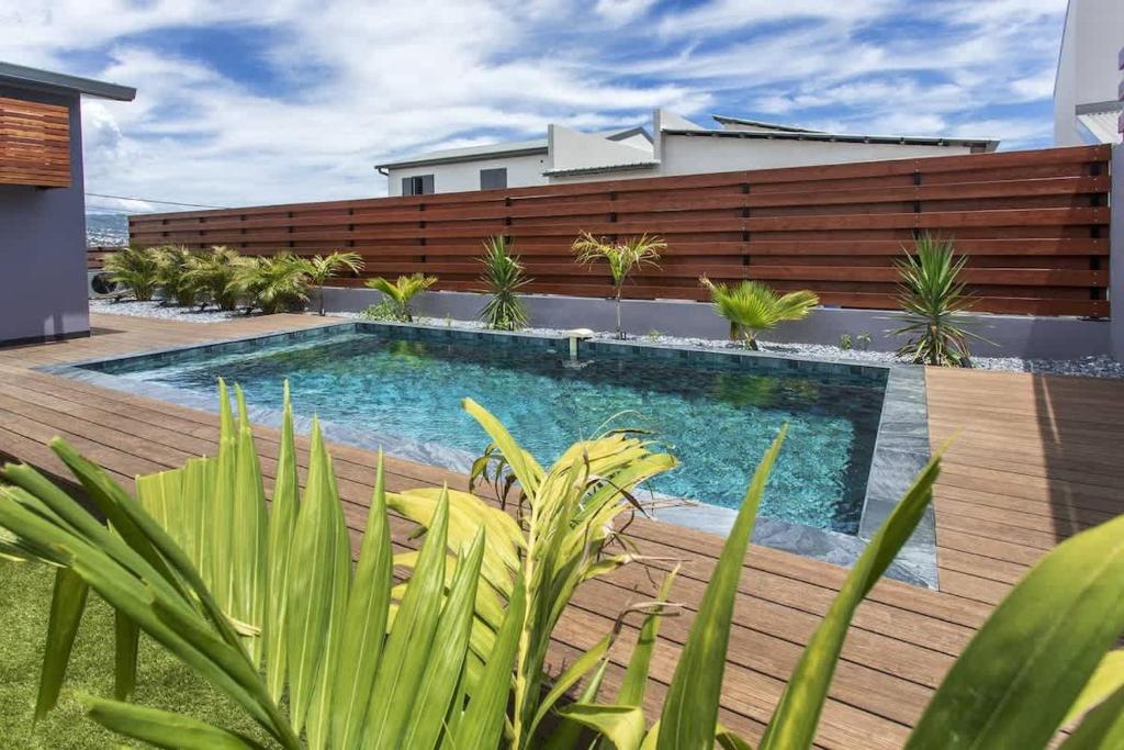 a swimming pool in a backyard with a wooden fence at VILLA BELLEVUE classée 5 Etoiles - 4 chambres - piscine chauffée proche de l'aéroport et du centre de St Denis in Sainte-Marie