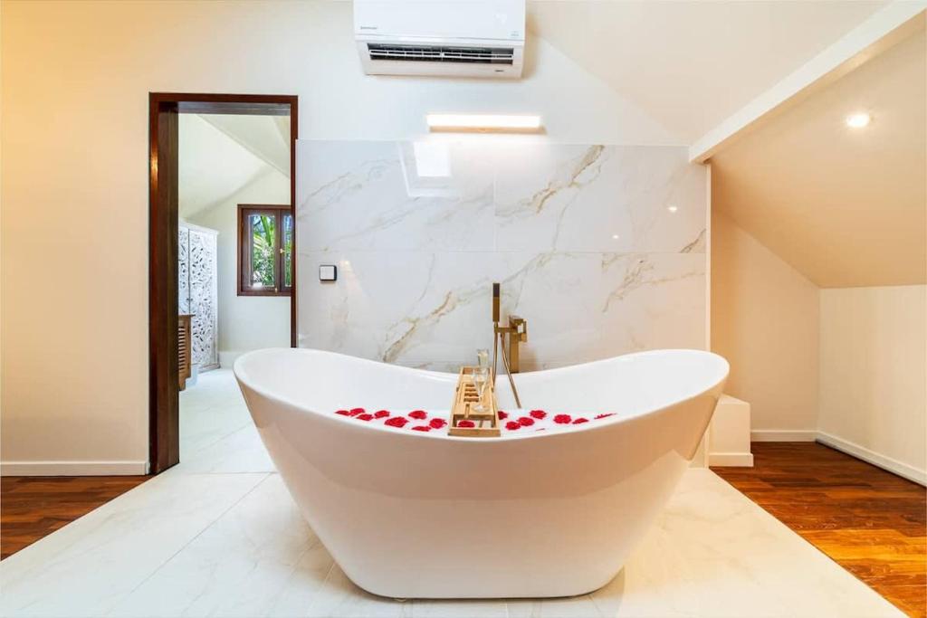a white tub in a bathroom with a marble wall at VILLA DU JARDIN ANGELIQUE classée 5 étoiles - 4 suites pouvant accueillir jusqu'à 8 personnes - piscine CHAUFFÉE située en plein centre-ville de St Pierre à 2 pas du lagon in Saint-Pierre