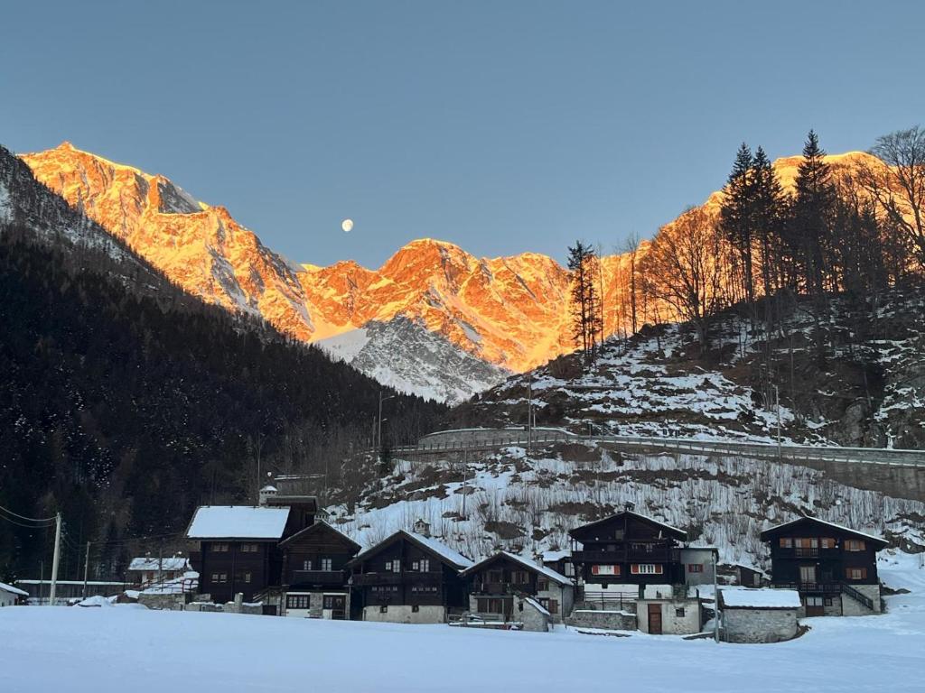 a group of buildings in the snow in front of a mountain at Incanto Walser Apartments Testa in Macugnaga