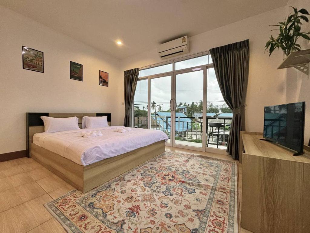 a bedroom with a bed and a large window at PROpaganda Guest House in Thongsala