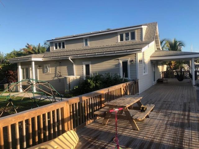 ein Haus mit einer Holzterrasse mit einem Picknicktisch in der Unterkunft Canal Front 3 bedroom 2 bathroom in Nassau