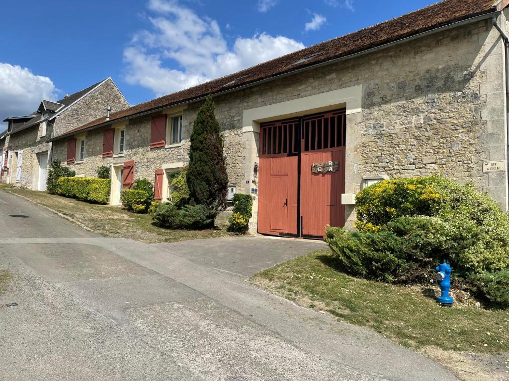 a brick building with a red door and a driveway at Le Havre de Braye in Braye-en-Laonnois