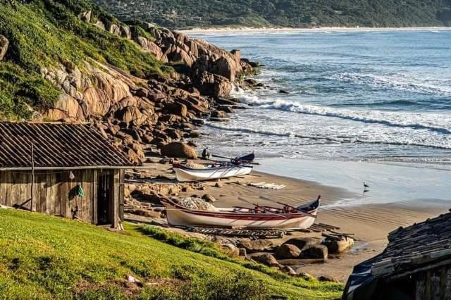 two boats sitting on the beach next to a house at Moradas do Maneca Chalé da Lagoa in Imbituba