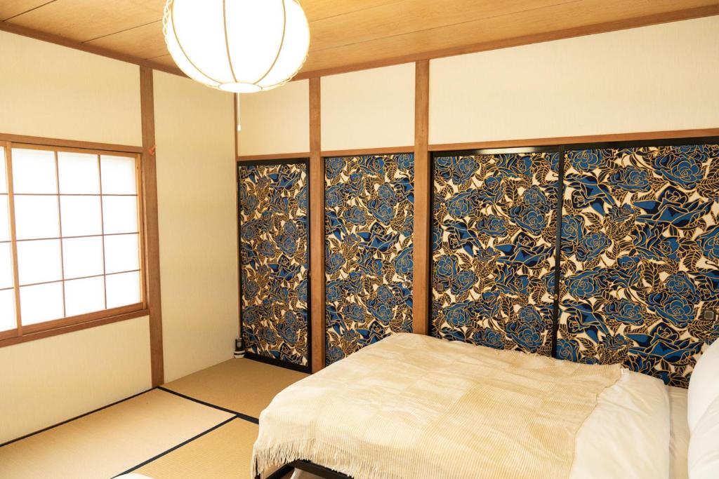 a bedroom with a bed and a wall with blue and gold wallpaper at The Sake Kura villa in Hakuba