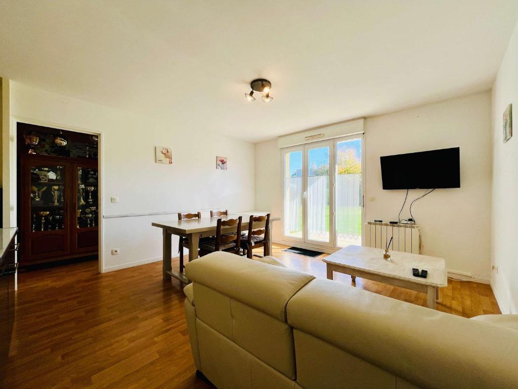a living room with a couch and a table at Le Petit Podium Cozy Ground Floor in Carentan