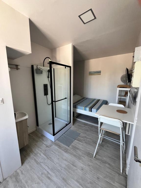 Habitación pequeña con cama, mesa y espejo. en Joli studio meublé proche de la plage, en Veules-les-Roses