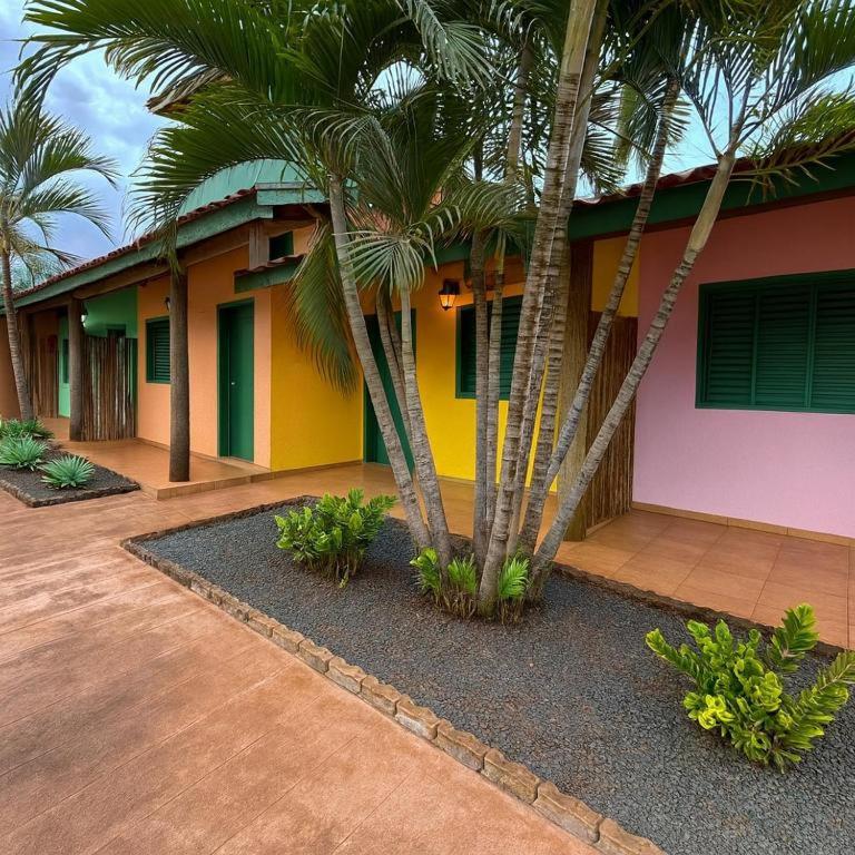 a house with palm trees in front of it at Pousada cores in Olímpia
