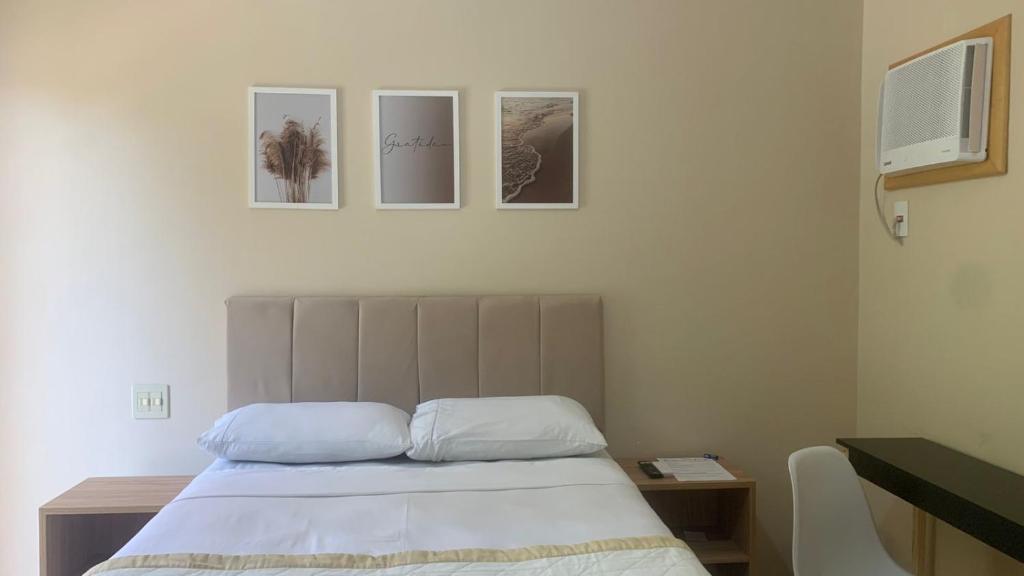 a bedroom with a bed with three pictures on the wall at Suíte de Casal Privativa com Sacada in Sao Jose do Rio Preto