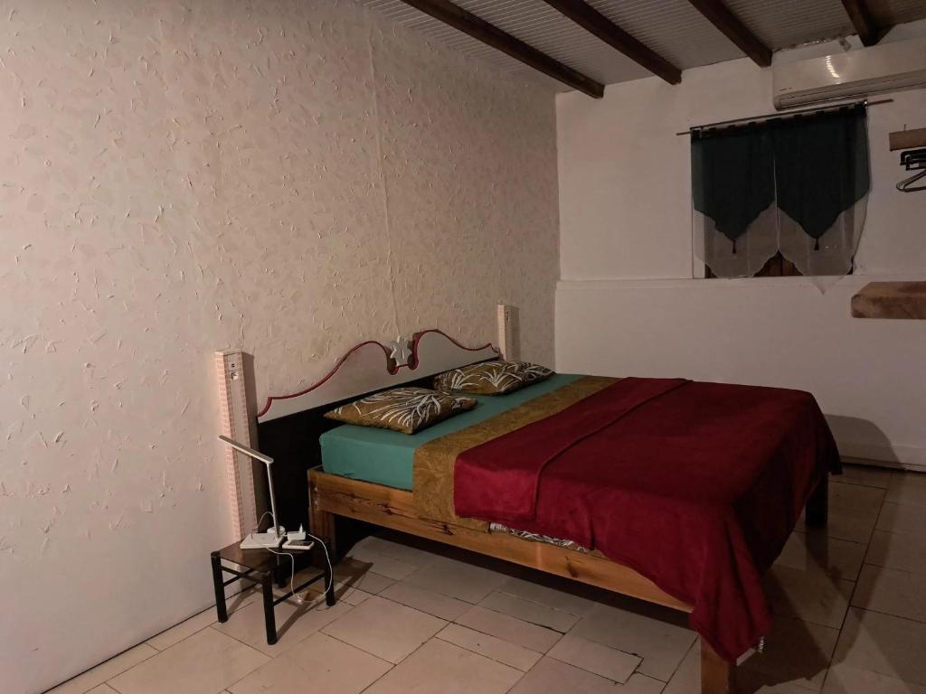 a bedroom with a bed with a red blanket at Bungalow cosy à Sainte-Anne avec jardin in Sainte-Anne