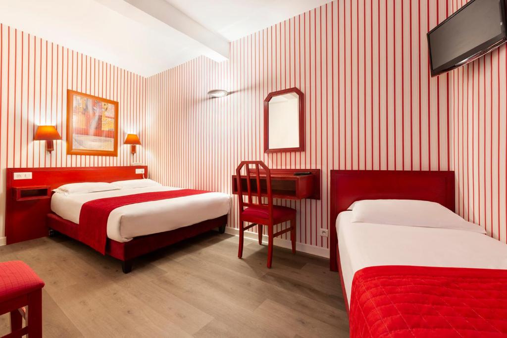 a bedroom with two beds and a chair and a tv at Maison Du Pré in Paris