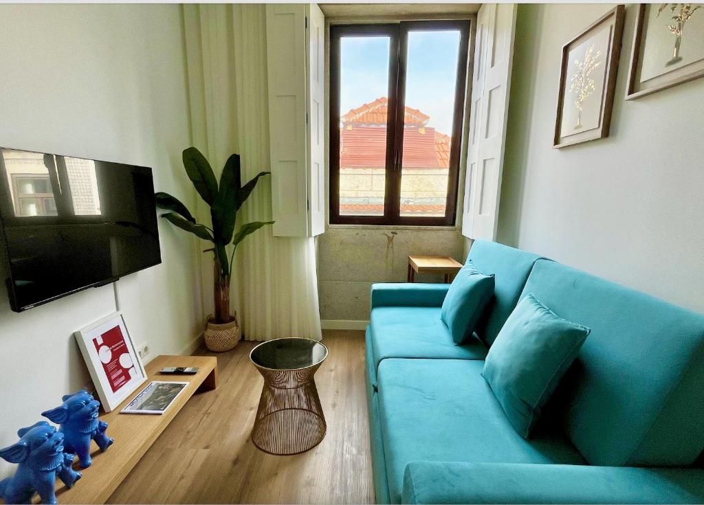 a living room with a blue couch and a tv at Water Vibes Porto by MyMoradia in Porto
