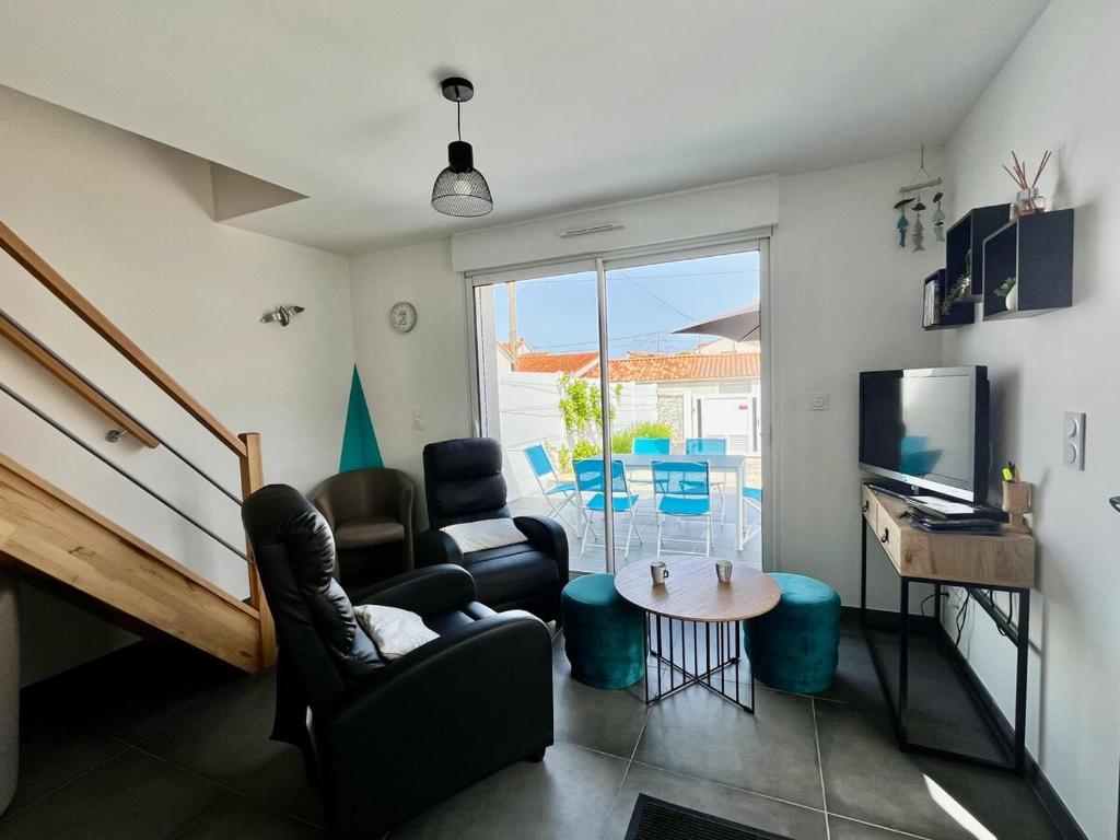 sala de estar con sillas, TV y mesa en Ti'Belot - calme près de la mer, en LʼAiguillon-sur-Mer