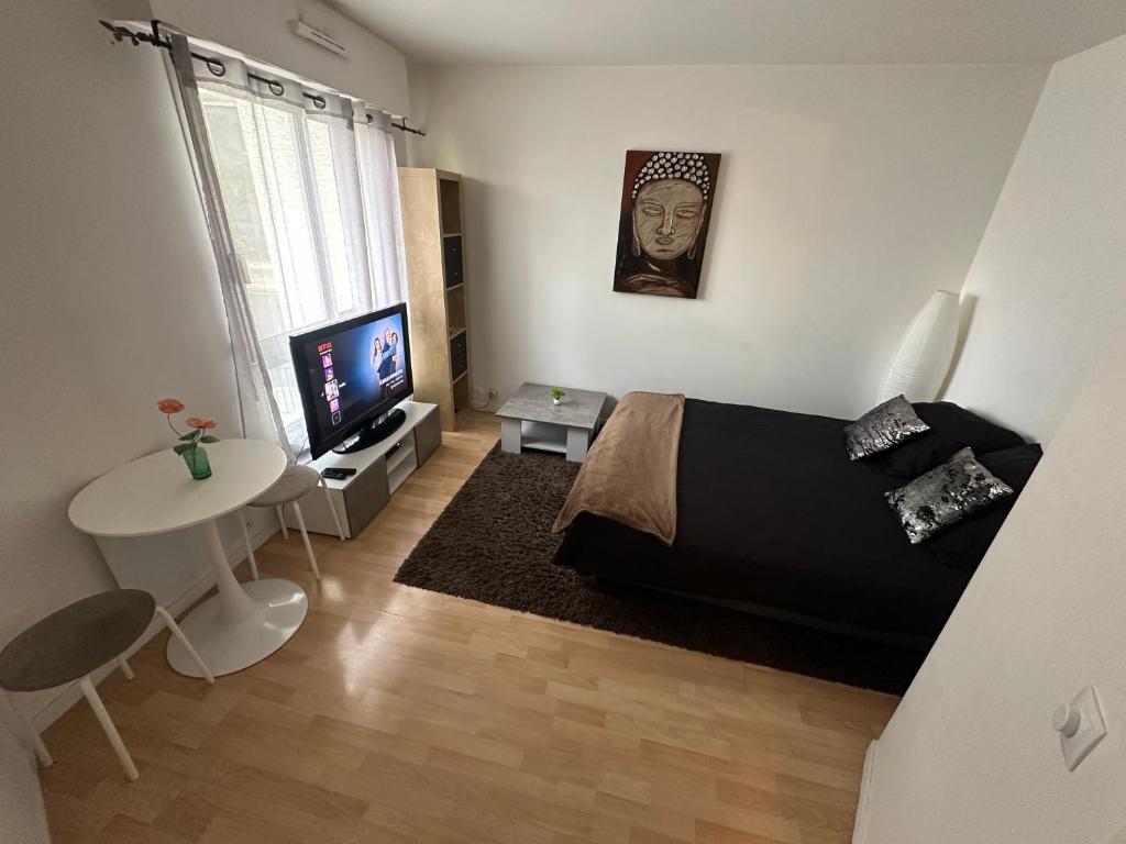 a bedroom with a bed and a tv and a table at Charmant studio à Paris in Courbevoie
