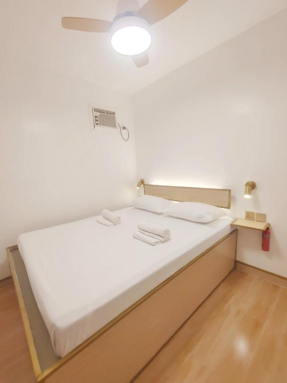 a bed with white sheets and a light on the ceiling at Pierside Inn in Cebu City