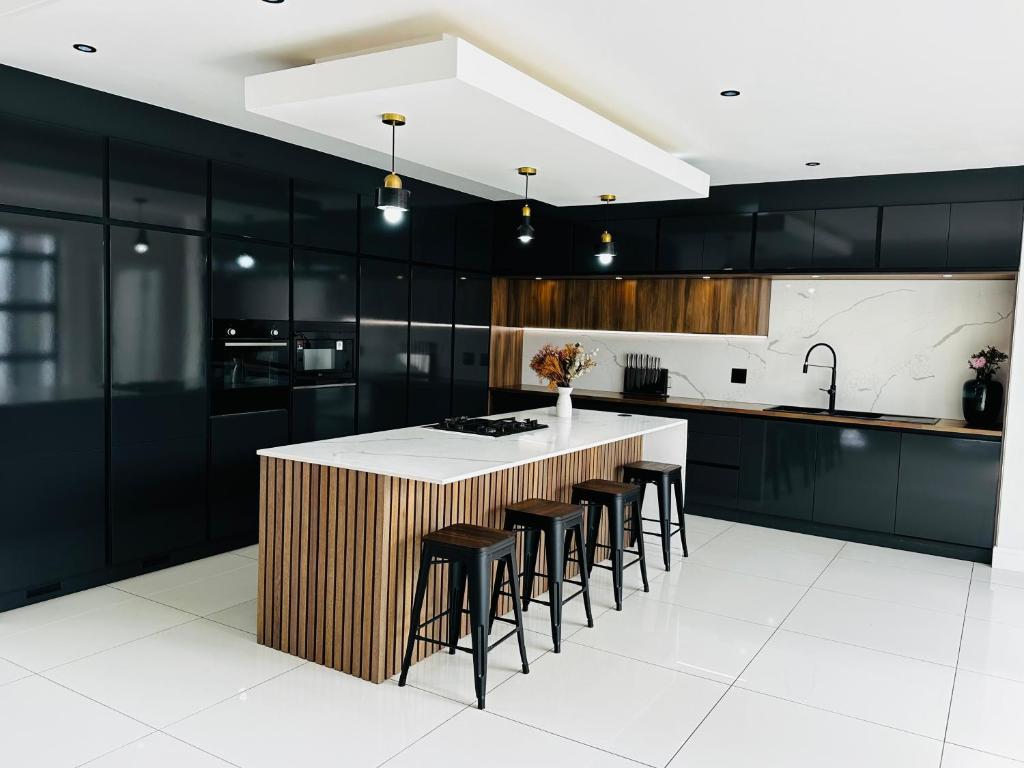 a kitchen with black cabinets and a counter with stools at Duinen Suites in Walvis Bay