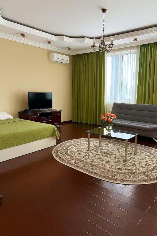 ein Schlafzimmer mit einem Bett, einer Couch und einem Tisch in der Unterkunft 38 Теплые апартаменты с 2 кроваями у Байтерека in Zhezdi