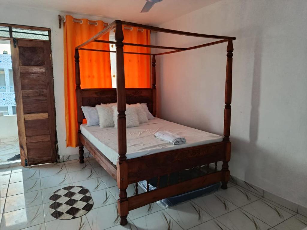 a bedroom with a four poster bed with an orange curtain at Watamu Plaza Studio 3 in Watamu