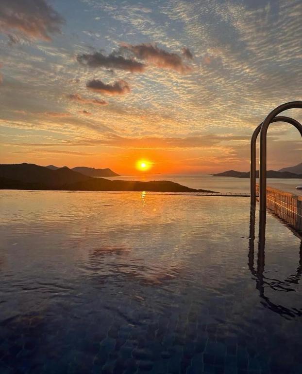 a swimming pool with the sunset in the background at VİLLA ÇAPA in Kaş