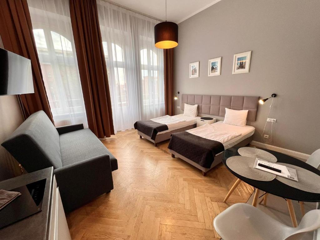 a hotel room with two beds and a couch at Wroclaw City Apartments in Wrocław