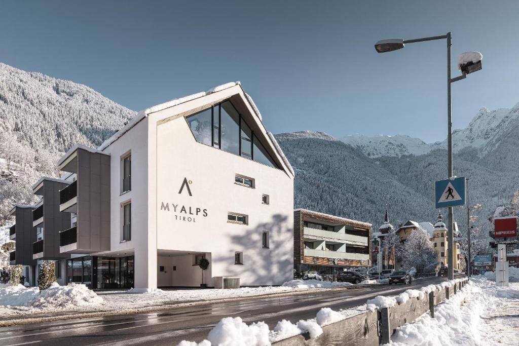 a building in the mountains with snow on the ground at MYALPS Tirol inklusive Sky- Wellness in Oetz