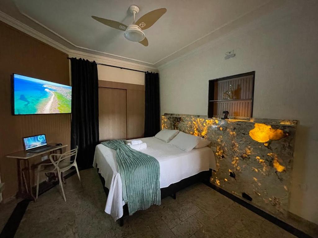 a hotel room with a bed and a desk and a television at Belíssimo Estudio Stella Maris in Andradina