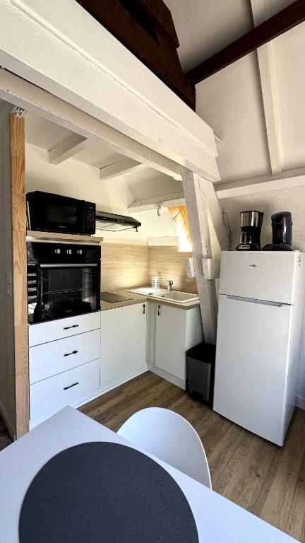 a kitchen with white cabinets and a stove top oven at Chalet Le Capéna Lac de Payolle in Campan