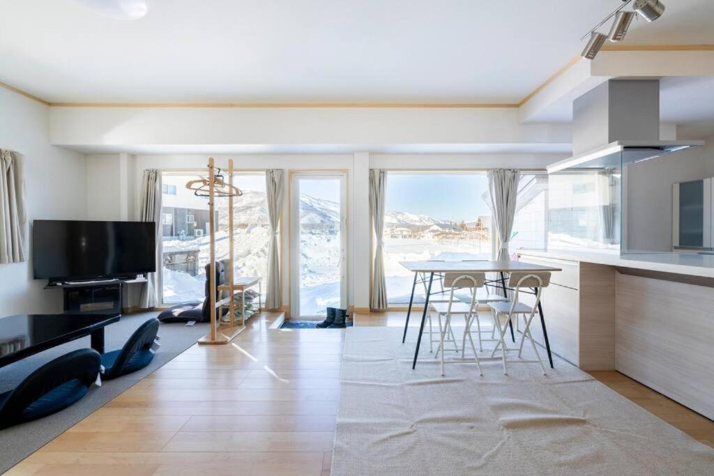 a living room with a table and a large window at Snow Fever - Clique in Hakuba