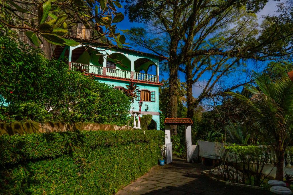 uma casa azul e branca com uma cerca e árvores em Refúgio na Serra de Petrópolis simples e acolhedor em Petrópolis