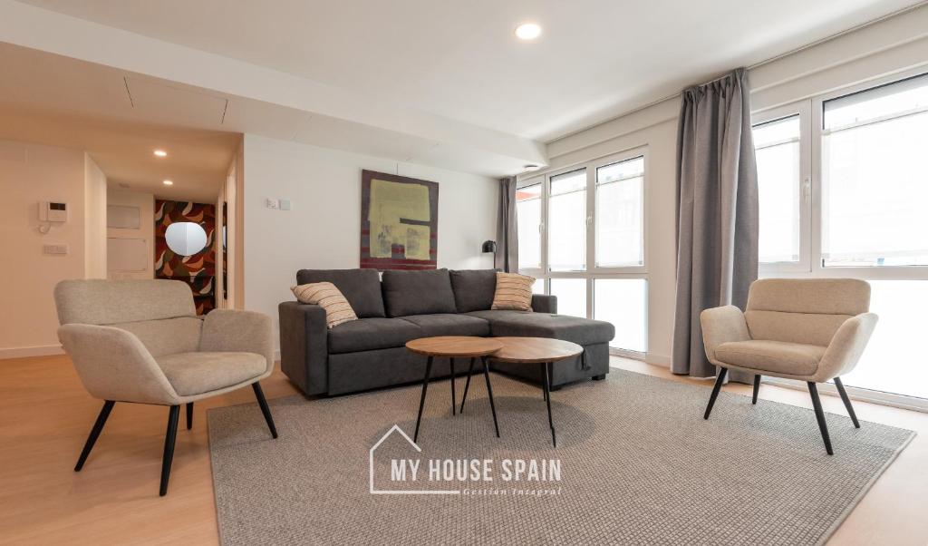 ein Wohnzimmer mit einer Couch und zwei Stühlen und einem Tisch in der Unterkunft MyHouseSpain - Edificio Vanguardia in Gijón