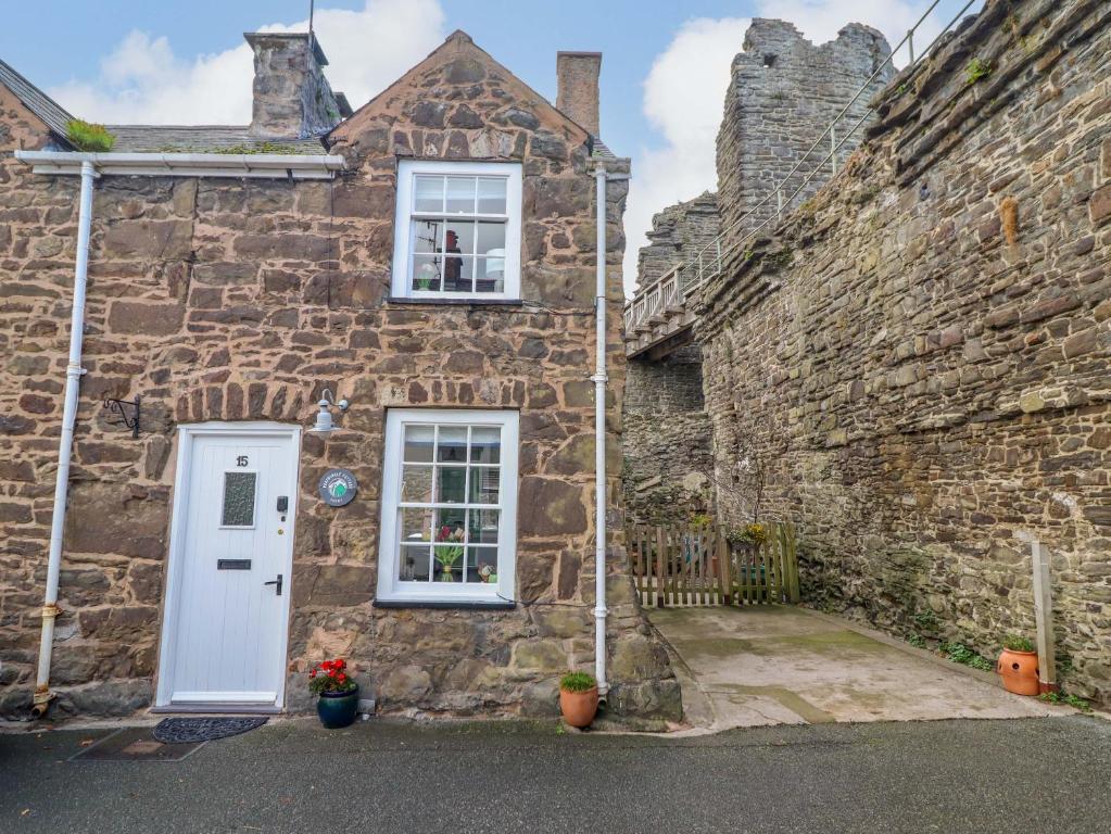 an old stone house with a white door and two windows at Periwinkle Cottage in Conwy