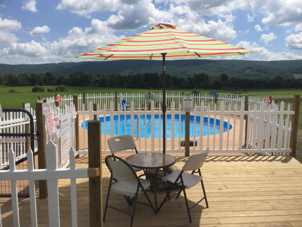 a table and chairs under an umbrella next to a pool at Apple Inn and Suites Cooperstown Area in Milford