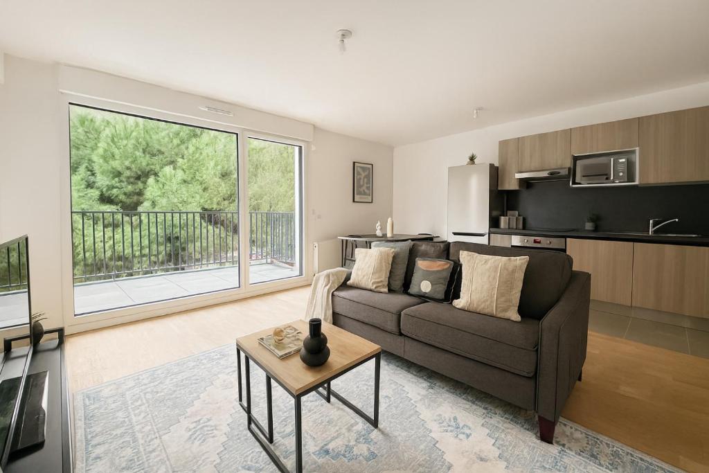 ein Wohnzimmer mit Sofa und Tisch in der Unterkunft Spacieux 3 chambres et lumineux à Montrouge in Malakoff