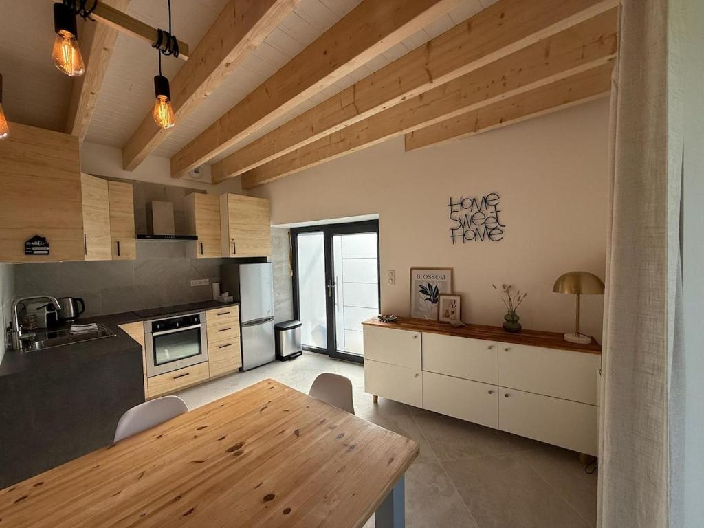 eine Küche mit Holzdecken und einem Holztisch in der Unterkunft Charmante maison rénovée avec terrasse et jardin in Crillat