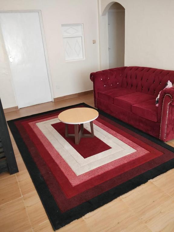 a living room with a red couch and a table at Swahiba's 254 in Keruguya