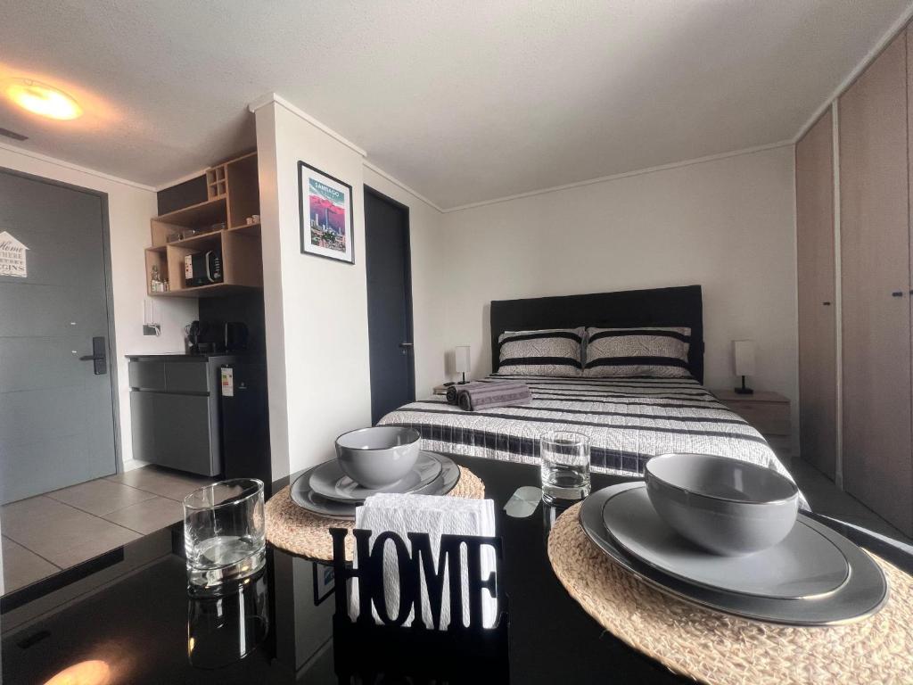 1 dormitorio con 1 cama y 2 platos en una mesa en Estudio cerca del Movistar Arena, en Santiago