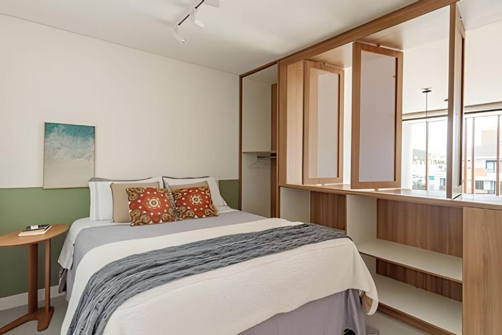 a bedroom with a large bed and a window at Loft Moderno, 500m Praia, Piscina, Sauna, WiFi 1GB in Florianópolis