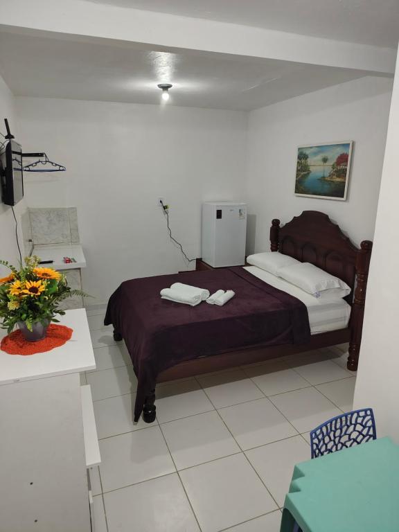 a bedroom with a bed and a table with a vase of flowers at suíte feliz in Belém