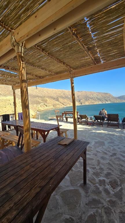 a wooden bench under a pavilion with a view of the water at Aloha chambres vue village in Imsouane