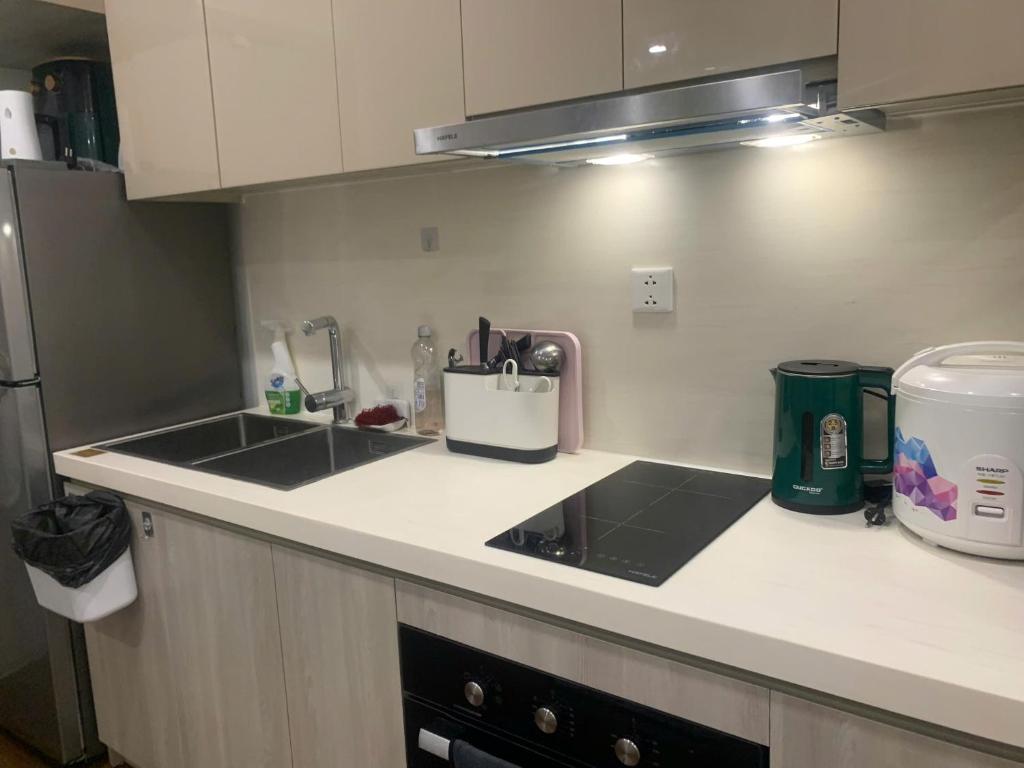 a kitchen counter with a sink and a refrigerator at Vinhomes Smart City by Chill D Homestay in Phú Thú
