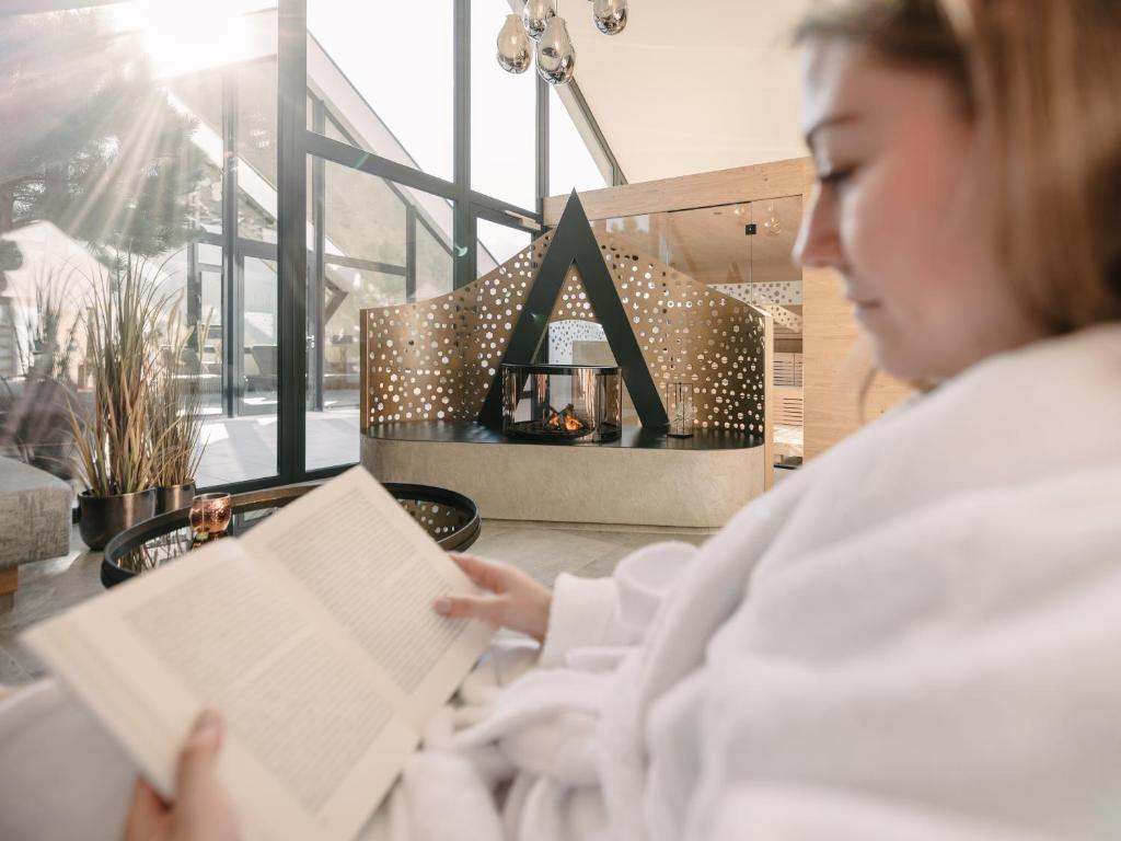 a woman reading a book in a room at MYALPS Tirol inklusive Sky- Wellness in Oetz