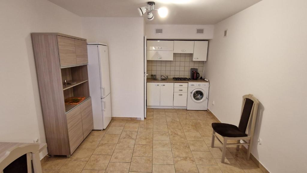 a small kitchen with a refrigerator and a chair at kawalerka w centrum Grajewa in Grajewo