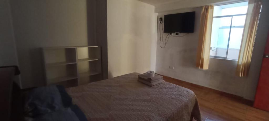 a bedroom with a bed and a television and a window at Apartment, with kitchen, garage and laundry in Tacna