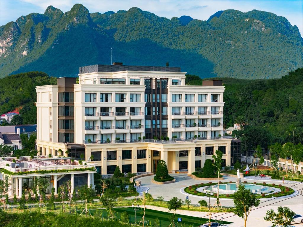 Un grand bâtiment blanc avec des montagnes en arrière-plan dans l'établissement Venusgiti Hot Spring Resort & Spa, à Hòa Bình