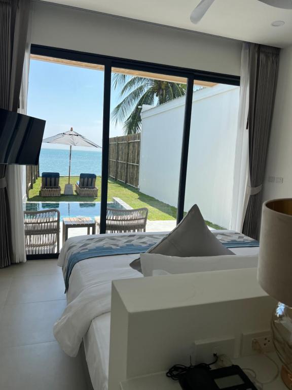 a bedroom with a bed and a view of the ocean at ThreeTreesSamuiPoolVilla in Ban Thung