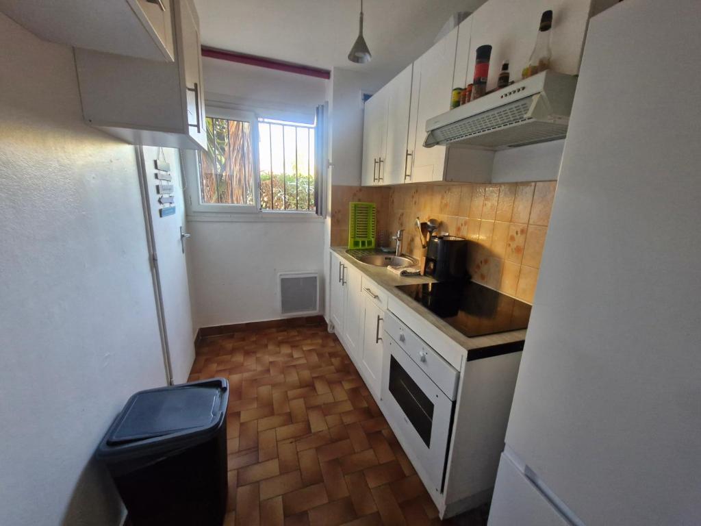 a small kitchen with white cabinets and a sink at Appartement Fréjus - deux chambres in Fréjus