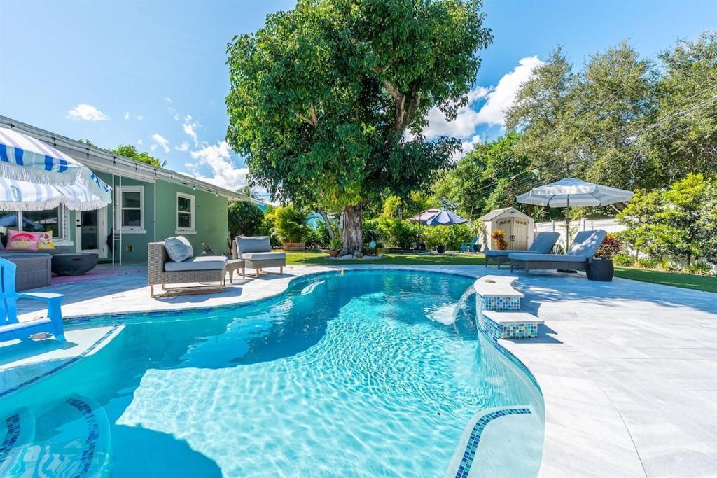 a swimming pool in a yard with chairs and a house at Relaxing Salt Pool & Spa, Walk to Key Lime House! in Lantana