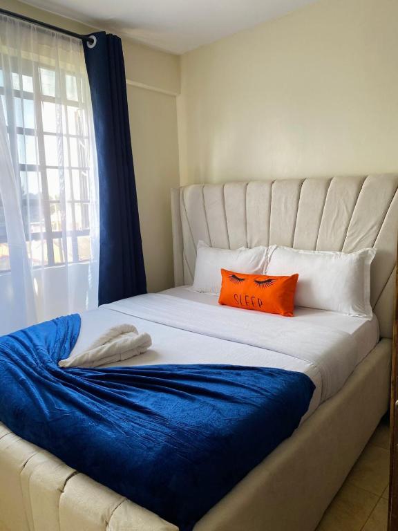a bed with two orange pillows on top of it at Studio Executive Serenity in Eldoret in Eldoret