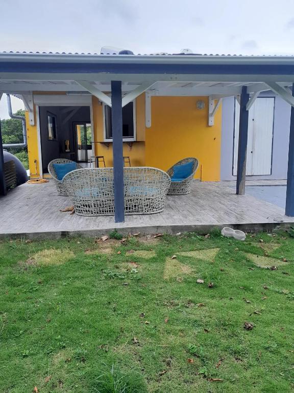 Un patio con sillas azules y una casa amarilla. en Appartement spacieux à Morne-à-l'Eau, 80 m², piscine privée, en Brion
